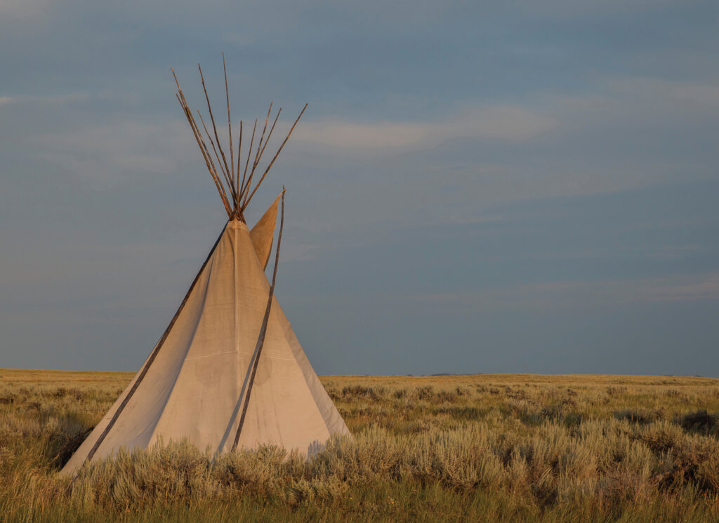A tipi at Antelope Creek glows during golden hour on the prairie.